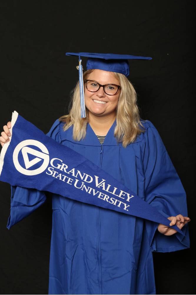 Woman poses with Grand Valley flag